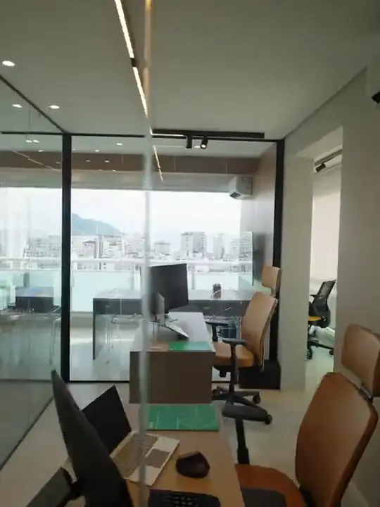 Escritório com salas envidraçadas, estações de trabalho e vista para a cidade