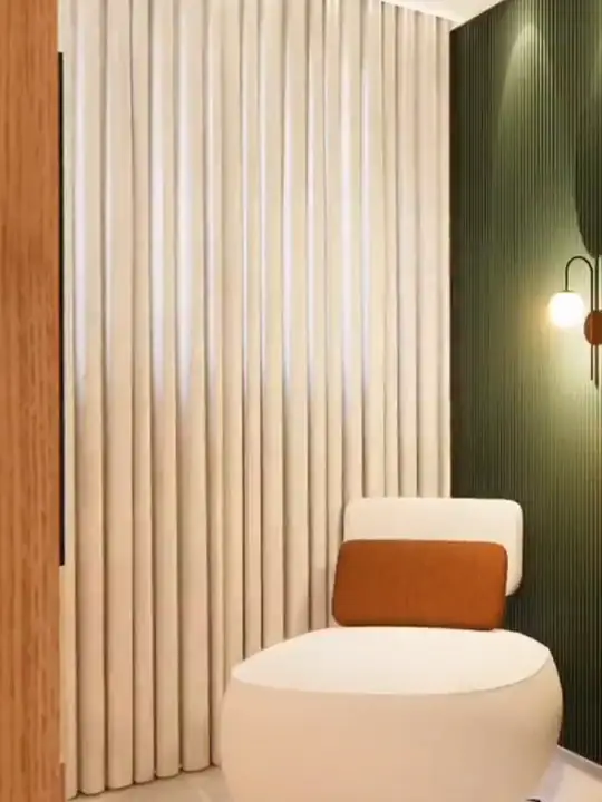 Projeto 3D de estar com poltrona curva clara, almofada terracota, cortina de linho e parede verde
