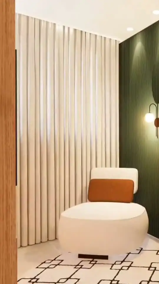 Projeto 3D de estar com poltrona curva clara, almofada terracota, cortina de linho e parede verde